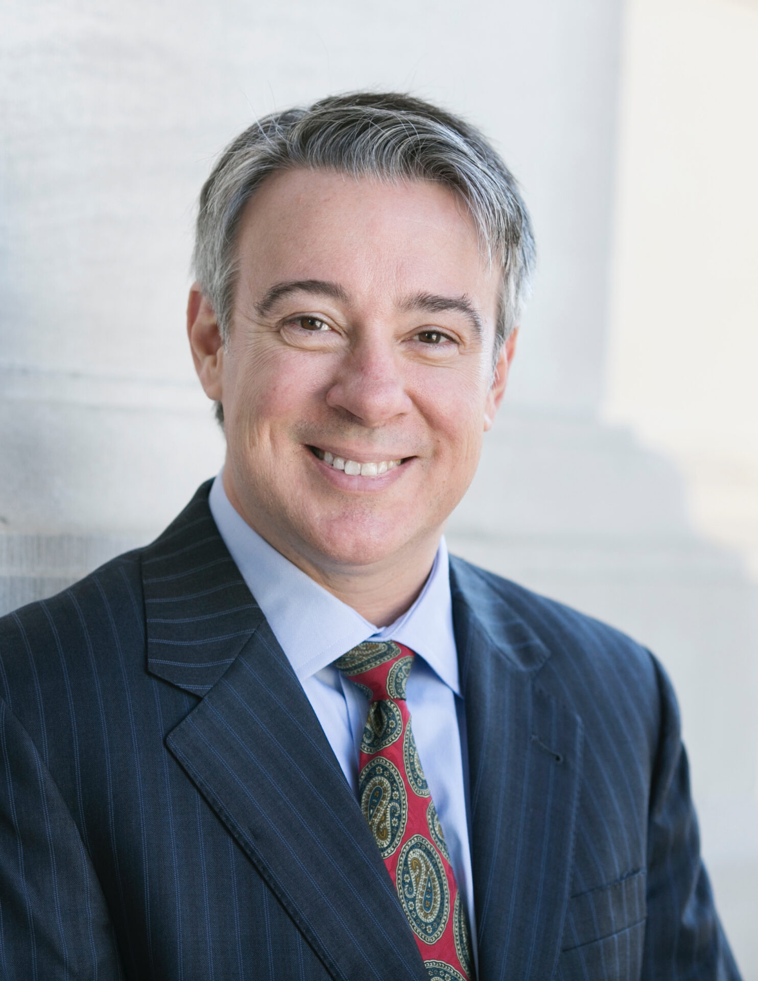 A man in suit and tie smiling for the camera.